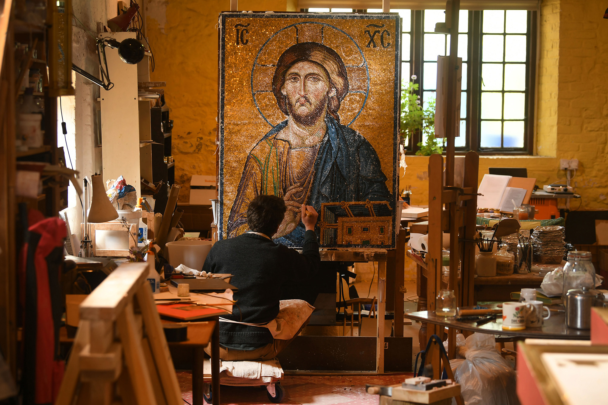 Eye for detail: Working in the soft light of the Malthouse studio in South Harting, Sussex, Iconographer Martin Earle trims in some of the 180,000 individually cut coloured tiles he’s used to replicate the famous 13th century Pantocrator mosaic depicting Christ on Judgement day.
 Taking four months to complete the twelve foot square mosaic resembling the 700 year old work found in the Hagia Sophia, Istanbul, the image, one of the most popular scenes in Byzantine religious art will sit above the desk of a London businessman when completed.©Russell Sach - 0771 882 6138